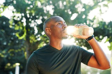 Outdoor, black man and fitness with drinking water for...