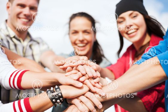 teenagers hands on top of each other outdoors