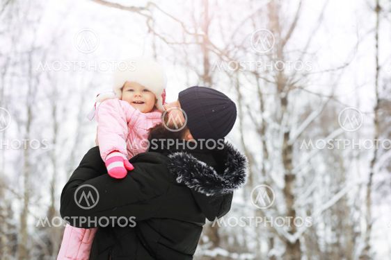 Happy family playing and laughing in winter outdoors in...