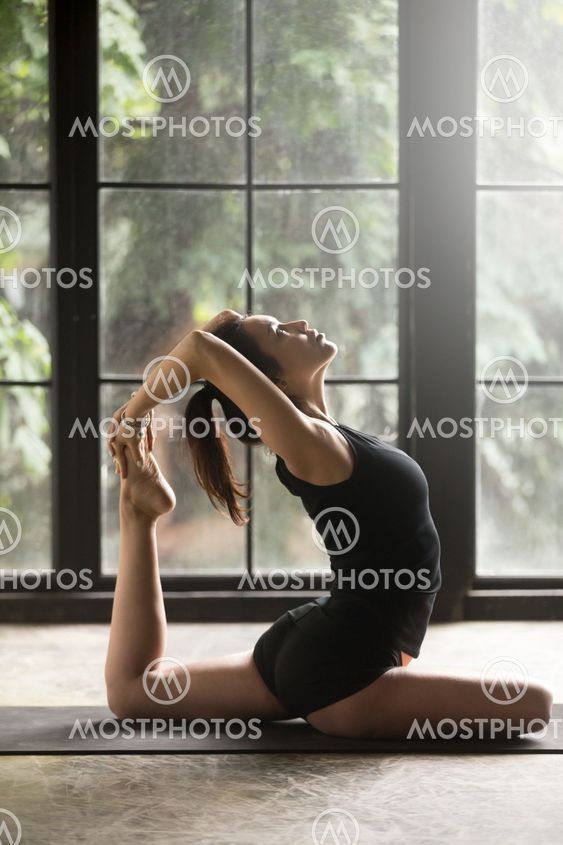 Young attractive woman in Eka Pada Rajakapotasana exercise, stud