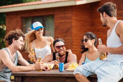 Smiling young friends sitting and drinking beer outdoors