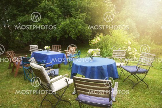Set up for a private garden party with tables, blue...