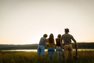 Group of friends in dusk of summer day looking to horizon