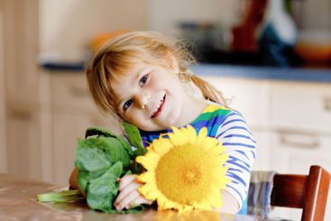 Adorable toddler girl and sunflower. Cute child holding...