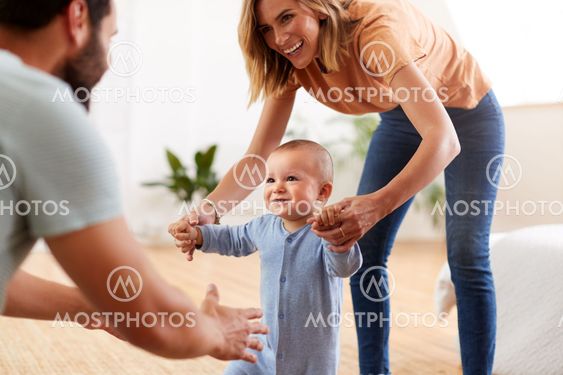 Parents At Home Encouraging Baby Son To Take First Steps