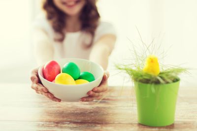 close up of girl holding bowl with colored eggs