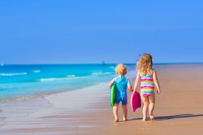 Children with surf boards on tropical beach