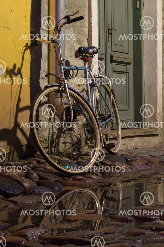 Vintage bike tied to the downpipe on cobbled street of old town
