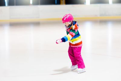Child skating on indoor ice rink. Kids skate.