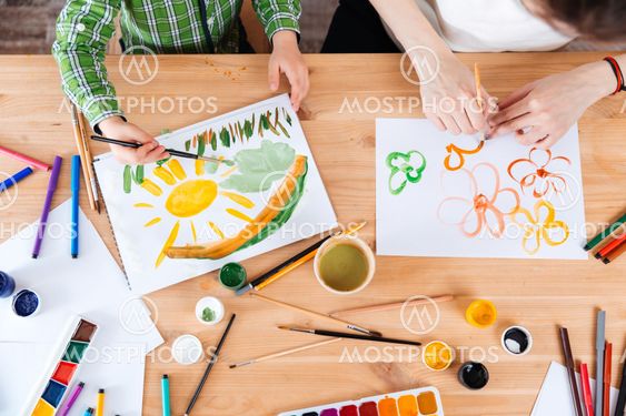 Hands of mother and son painting bright colorful pictures