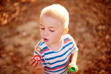Bubbles, blowing and child in field with fun, sunset...