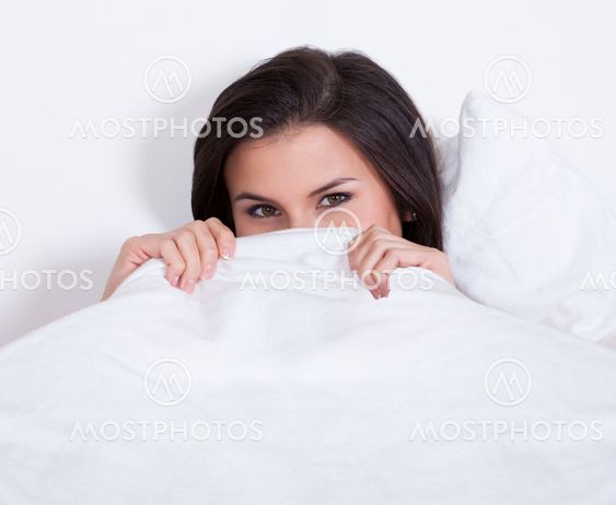 Pretty woman snuggling down in bed
