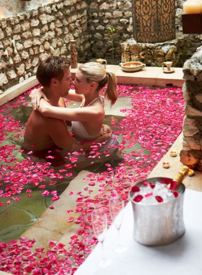 Couple Relaxing In Flower Petal Covered Pool At Spa