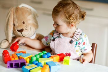 Adorable toddler girl with favorite plush bunny playing...
