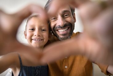 Little girl and father looking at camera through joined...
