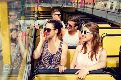 group of smiling friends traveling by tour bus