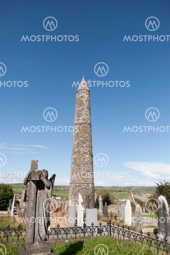 Angel statue before an Ancient round tower