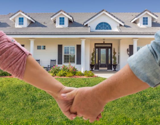 Couple Holding Hands Approaching Front Door Of New House