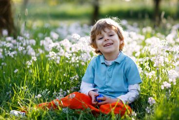 little kid boy having fun with traditional Easter egg hunt