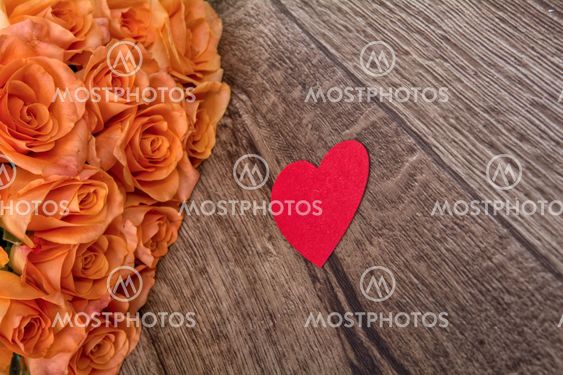 Orange roses and heart on a wooden background