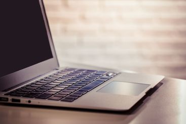 Laptop resting on a wooden table with a soft textured...