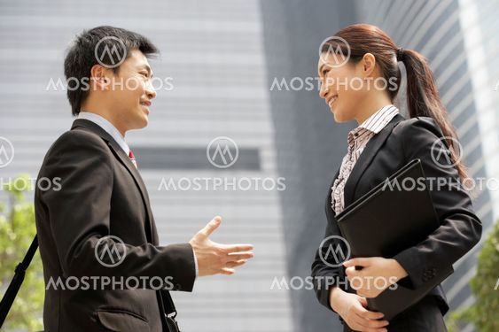 Chinese Businessman And Businesswoman Having Discussion Outside Office