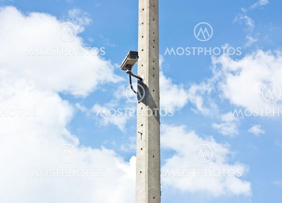 Video surveillance camera attached to electrical pole with blue sky background