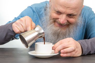 joyful coffee preparation: smiling bearded elderly man...