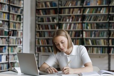 Student prepare for test writing in copybook sit in library