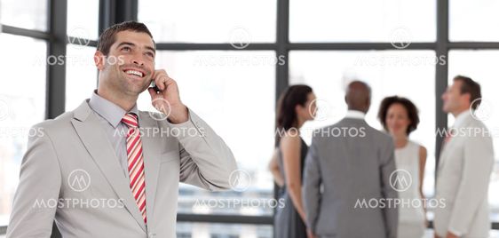 Dynamic businessman holding a phone at workplace with his colleagues