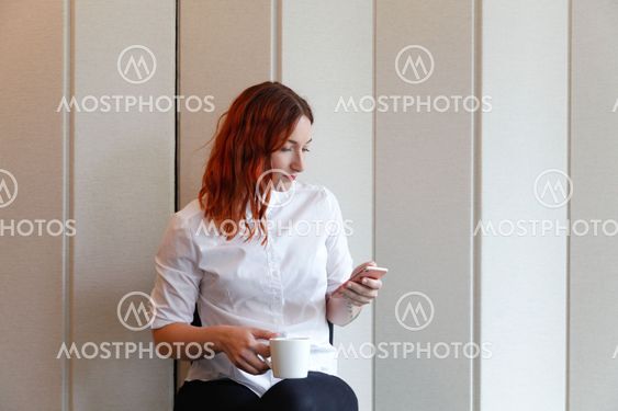 Kvinna på kontor kollar telefonen