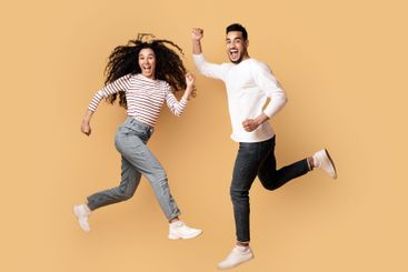 Excited Overjoyed Arab Couple Jumping In Air Over Yellow...