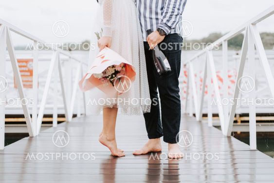 Feet of the newlyweds on the pier. Legs of the bride and...