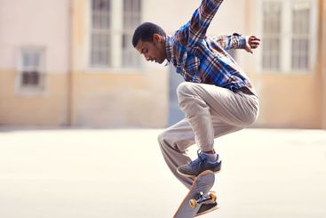 Man, skateboard and jump at urban skatepark, sports and...