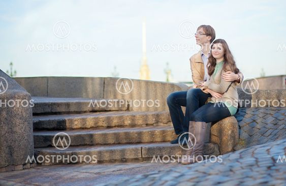 Couple sitting on the embankment with view to Peter and Paul Fortress in Saint-Petersburg