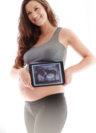 Woman, pregnant and satisfied with scan on tablet at...