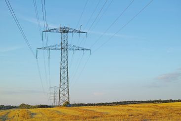 Electricity pylons, tower and countryside with blue sky,...