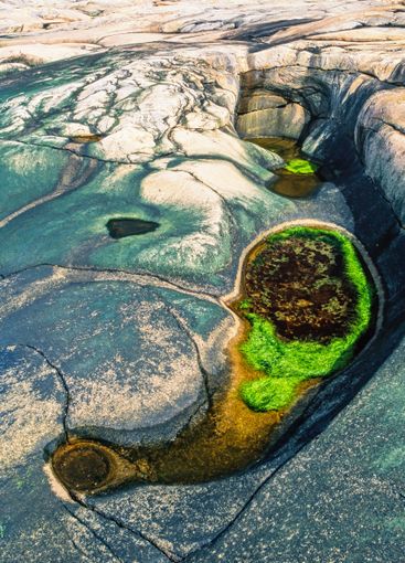 Rock crevice with green algae in the water in a rocky...