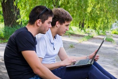 Young men sitting on the ground using laptop