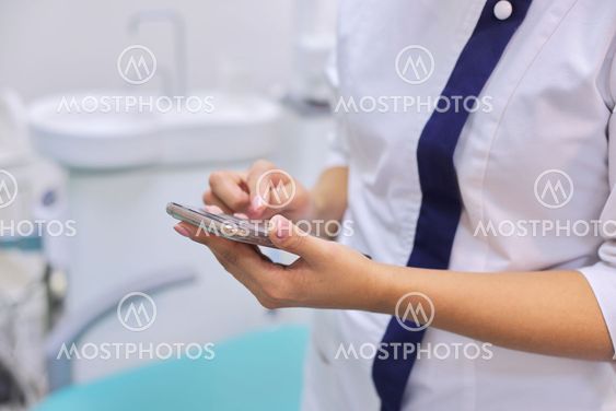 Close up of female doctors hand with mobile phone...