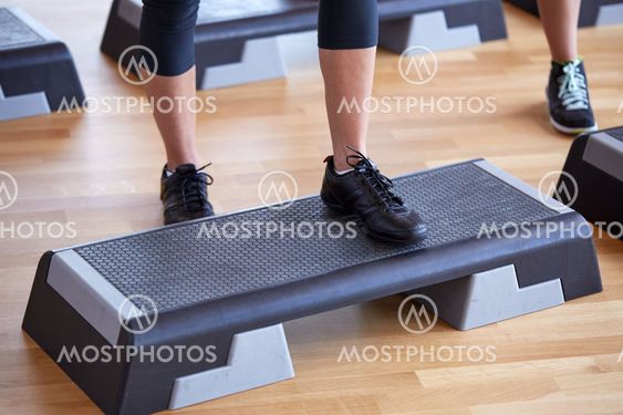 close up of women exercising with steppers in gym