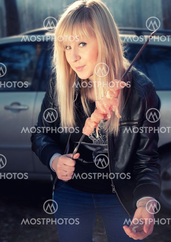 A young woman in the forest cooking shashlik