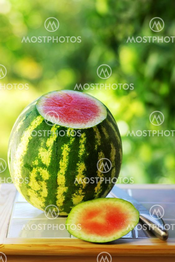 Watermelon and knife on table.