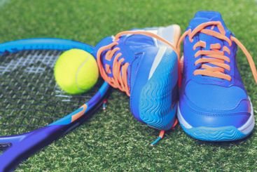 Bright blue tennis shoes and a racket with a yellow ball...