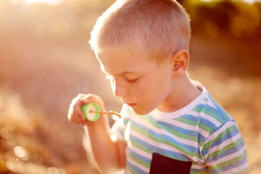 Bubbles, play and kid in park with fun, sunset adventure...