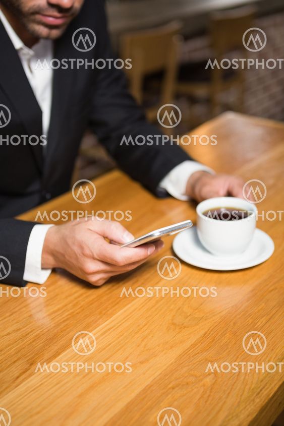 Businessman using smartphone and having coffee
