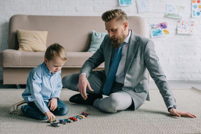 businessman in suit and little son playing with toy cars...