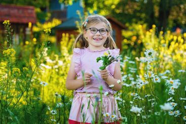 Little girl with eyeglasses holding bouquet of...