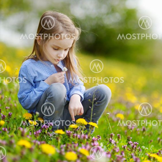Adorable girl in blooming dandelion flowers