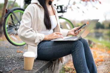 A woman in jeans is using the laptop while holding...